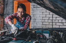 Female mechanic working on engine in a brick garage
