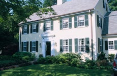A center hall Colonial-style home with trees in front yard