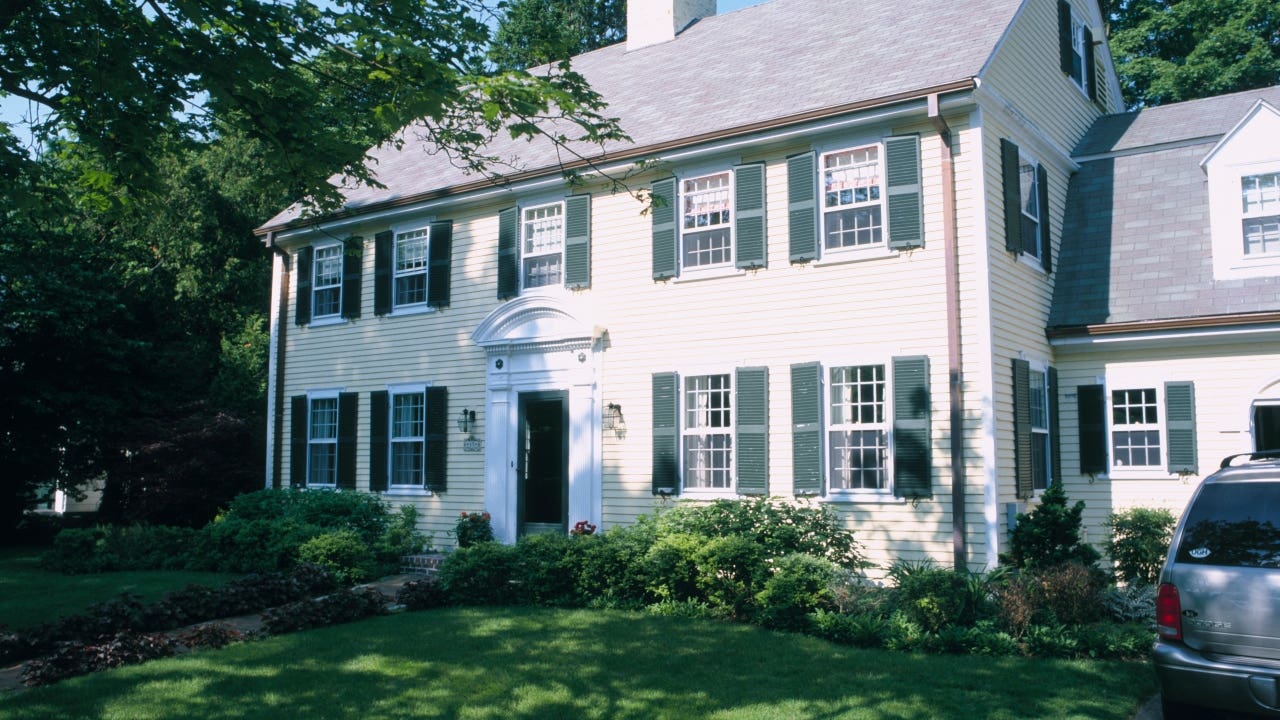 A center hall Colonial-style home with trees in front yard