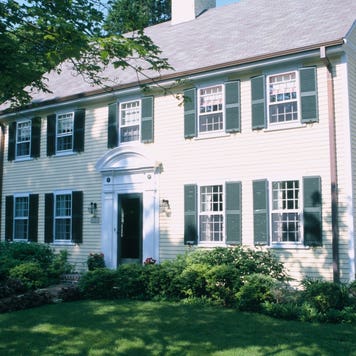 A center hall Colonial-style home with trees in front yard