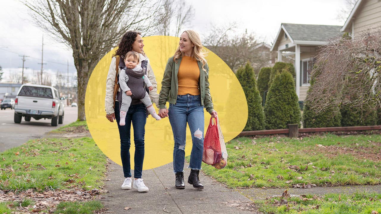 couple walking on a sidewalk with a baby and shopping bags