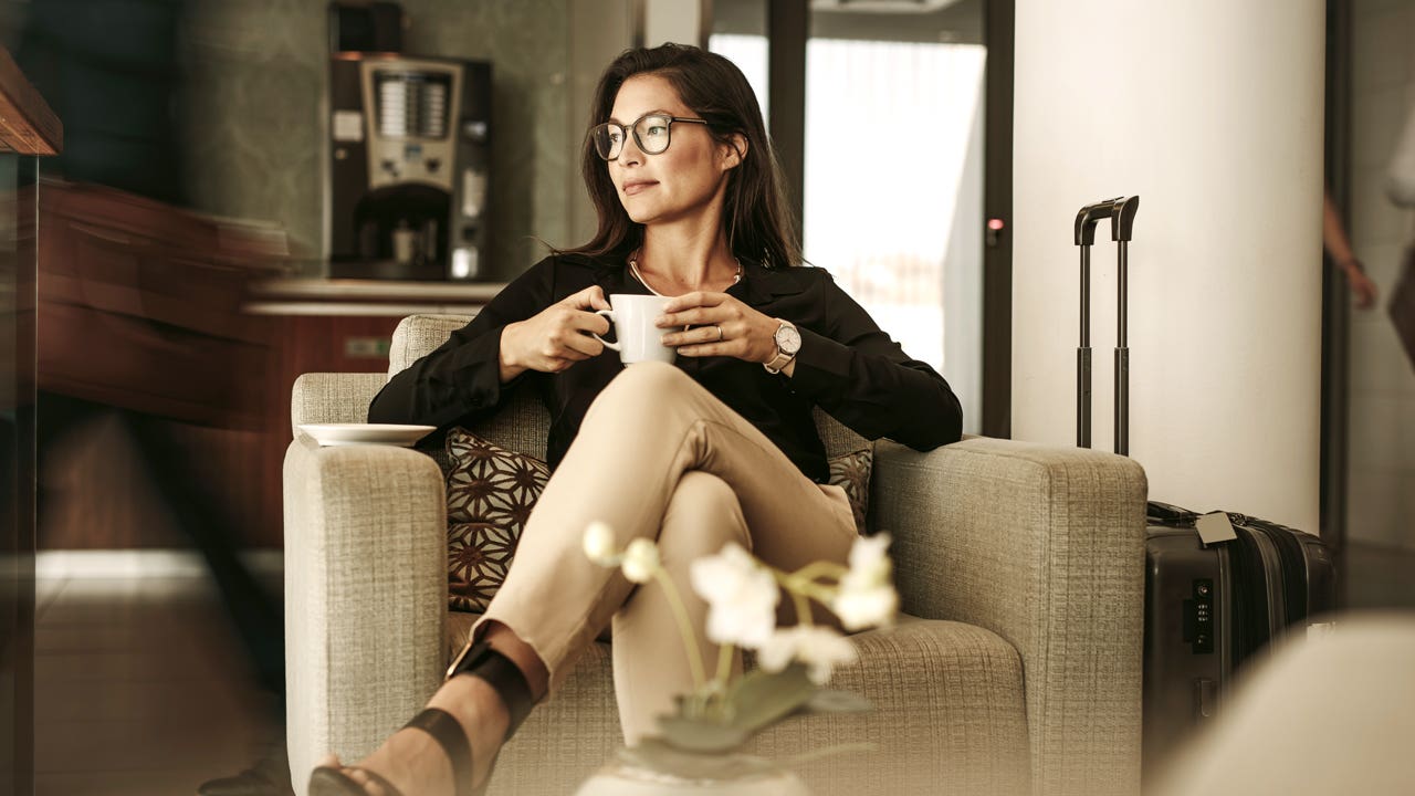 woman holding coffee cup and sitting in airport lounge