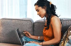 young woman using laptop and credit card in living room