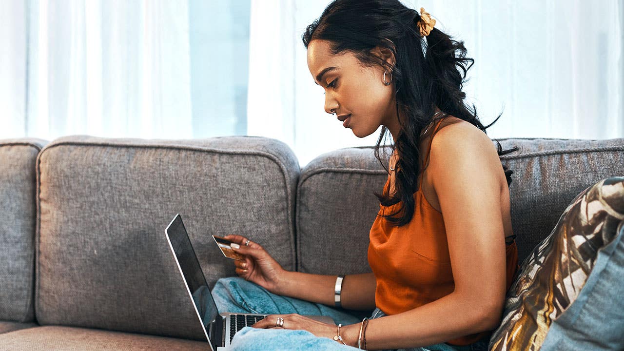 young woman using laptop and credit card in living room