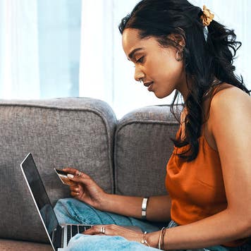 young woman using laptop and credit card in living room