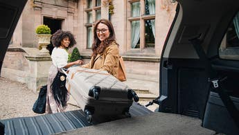 two girls unloading a car trunk at a hotel