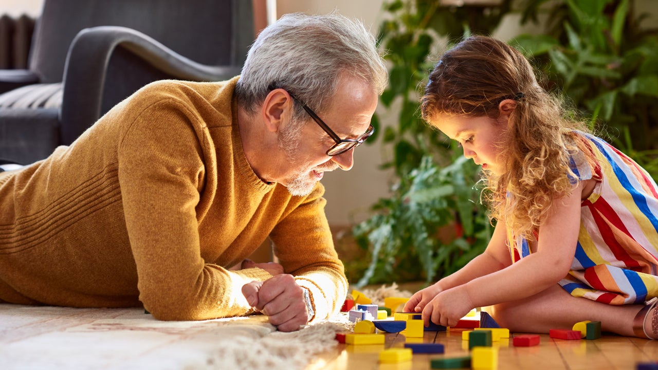 grandfather and granddaughter playing with wooden blocks in living room