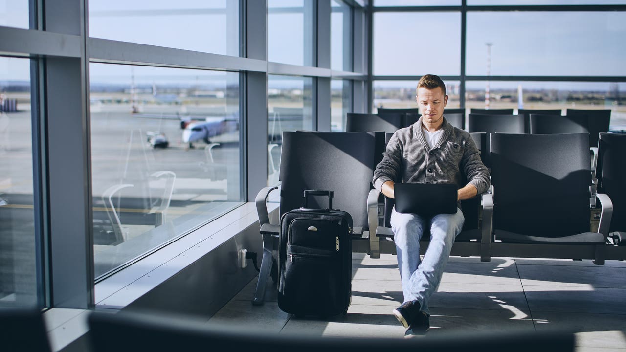 man sitting in airport and working on computer