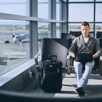 man sitting in airport and working on computer