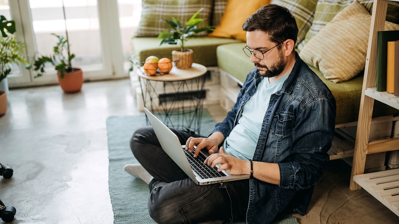 man sitting on the floor and working on laptop