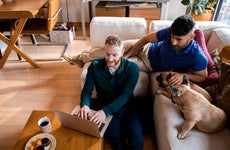 couple using laptop while sitting with their dogs in their living room