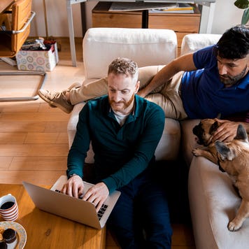 couple using laptop while sitting with their dogs in their living room