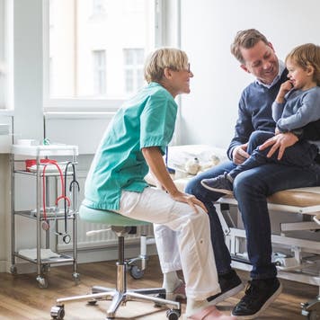 Doctor talks to father and son in clinic