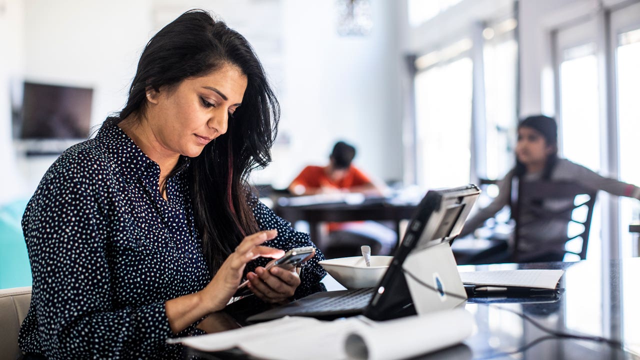 woman sitting in her kitchen and looking at her phone