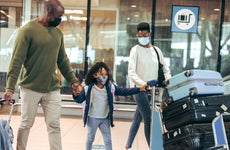 family of three walking through airport with luggage