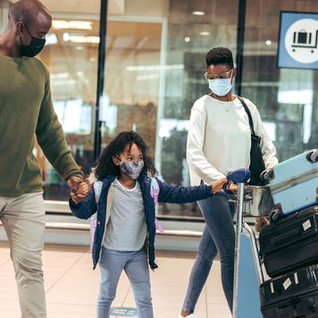 family of three walking through airport with luggage
