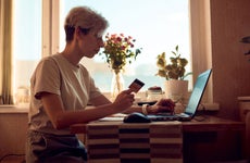 woman working on laptop at home while holding credit card