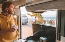 Man drinks coffee in his van, sea view