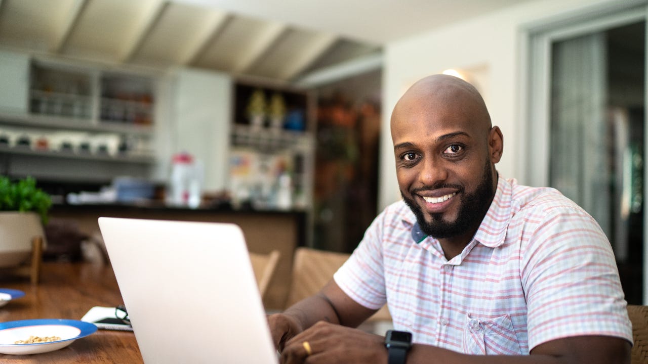 A young man with a laptop works from his home office