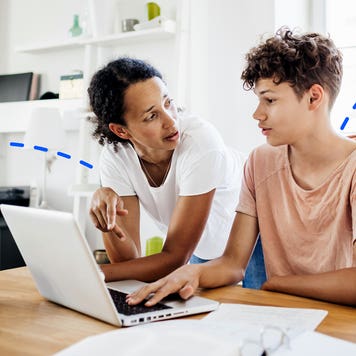 mother and teenage son talking and looking at computer