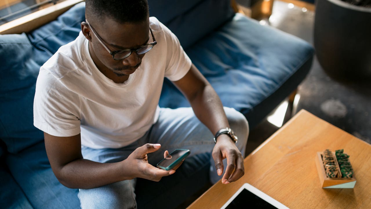 man sitting on couch and looking at his phone