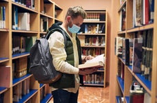 College student looks at books in a library