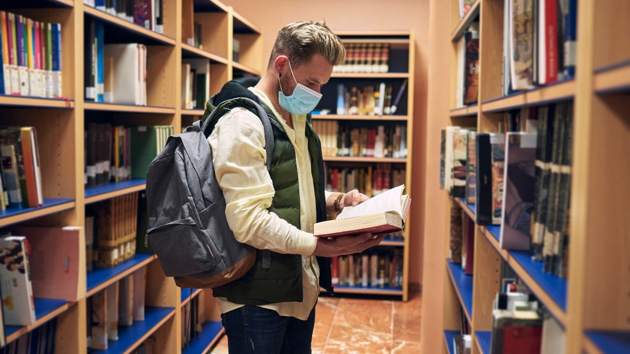 College student looks at books in a library