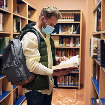 College student looks at books in a library