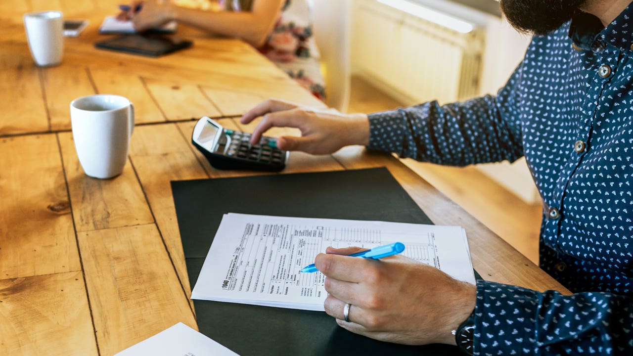 man working on tax forms with calculator