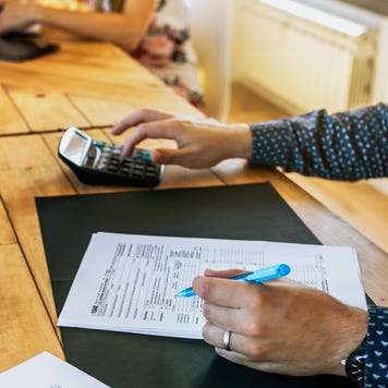 man working on tax forms with calculator