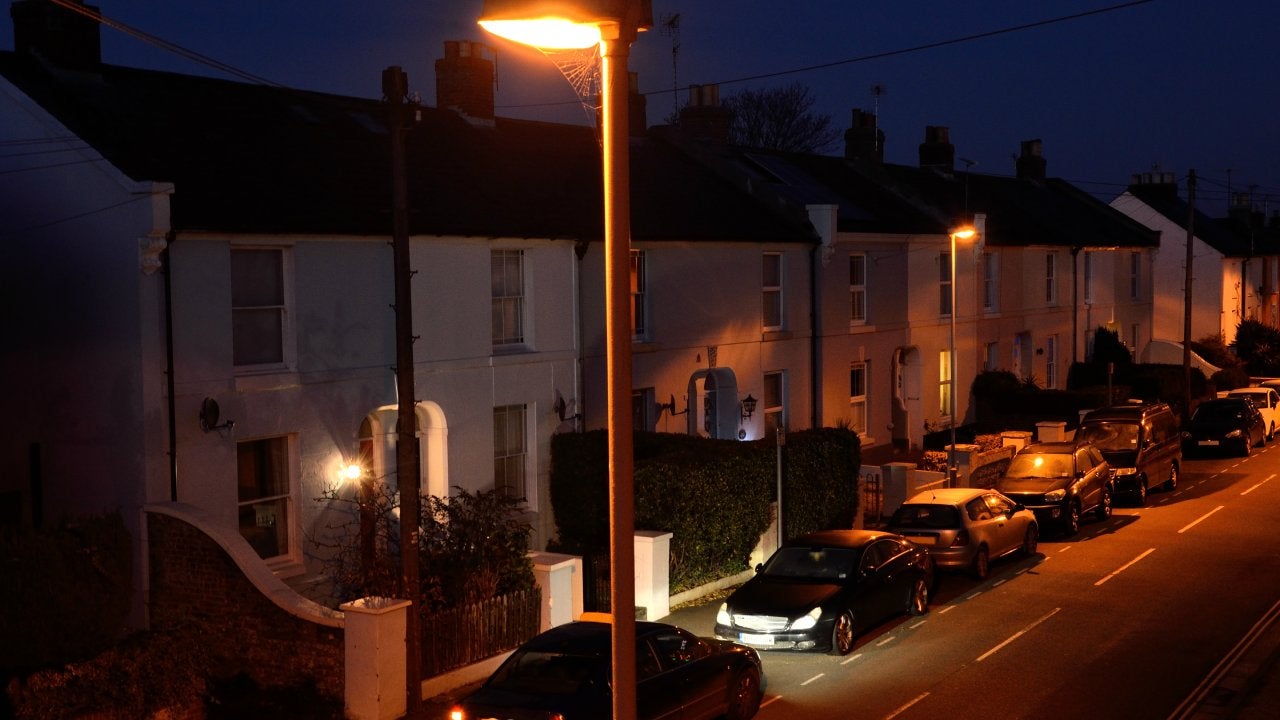 A car arrives in front of a row of terraced cottages as night descends.