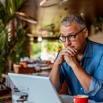 A businessman sits at a table with his laptop