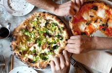 Hands Reach for Naples-Style Pizza at a restaurant
