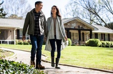 Couple walking in front of house