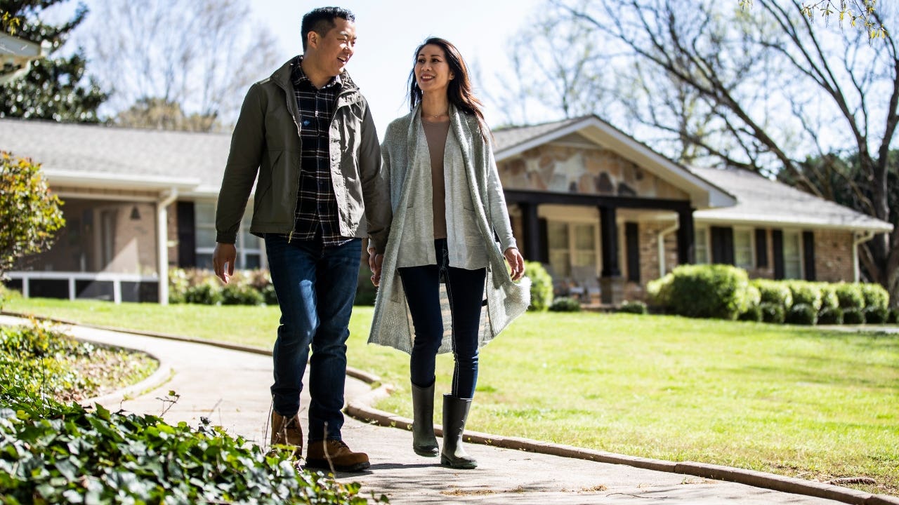 Couple walking in front of house