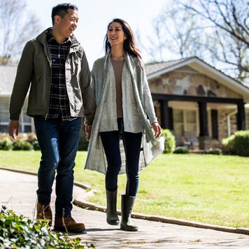 Couple walking in front of house