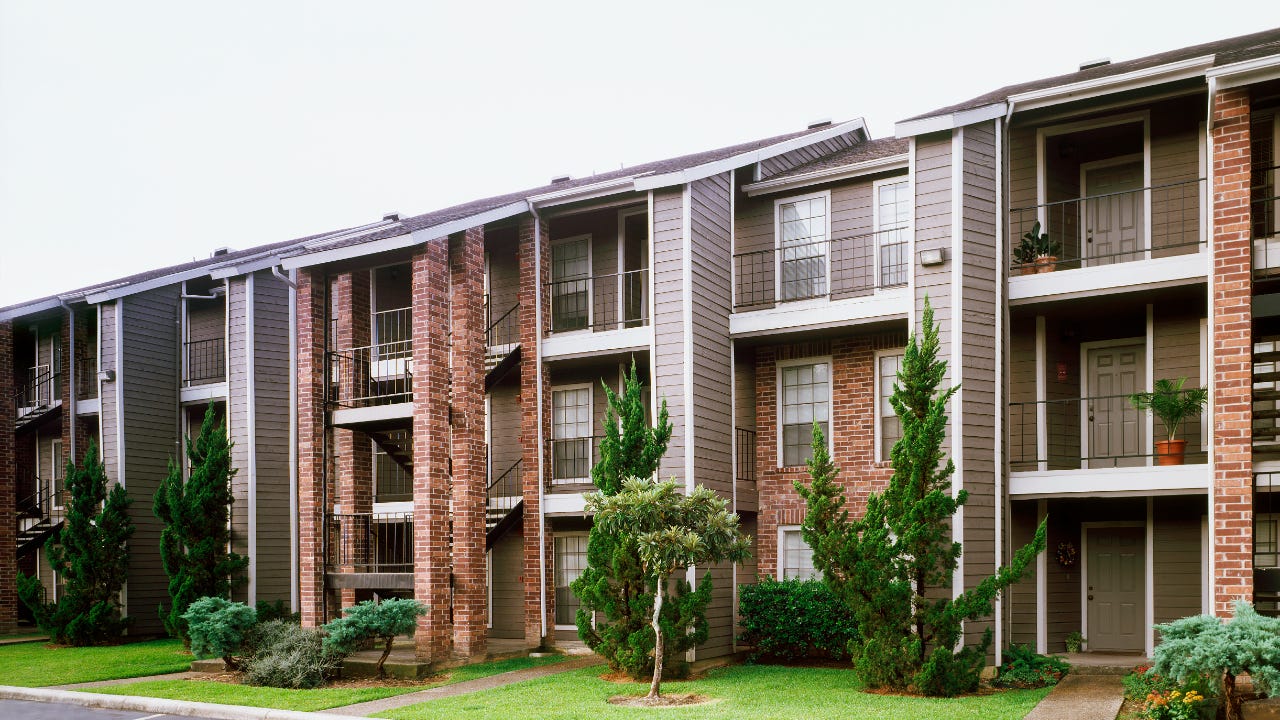 Front view of brick and siding condominium buildings from parking lot