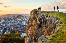 Group of people walking along cliff edge looking at Edinburgh city views