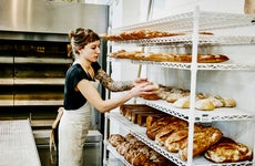 female baker placing bread to cool on a rack in bakery