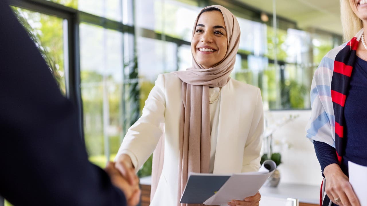 Woman shakes a hand during a job interview