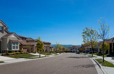 Suburban homes on a street under a blue sky with mountains in the distance