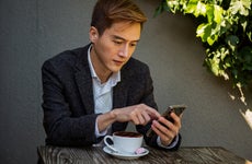 man sitting at outdoor cafe table and looking at his phone