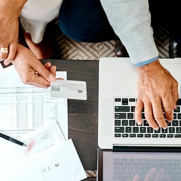 High angle shot of a couple using a laptop and credit card while sorting their finances together at home