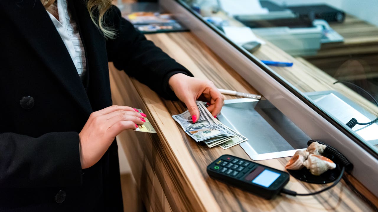 close up of woman handing cash at bank counter