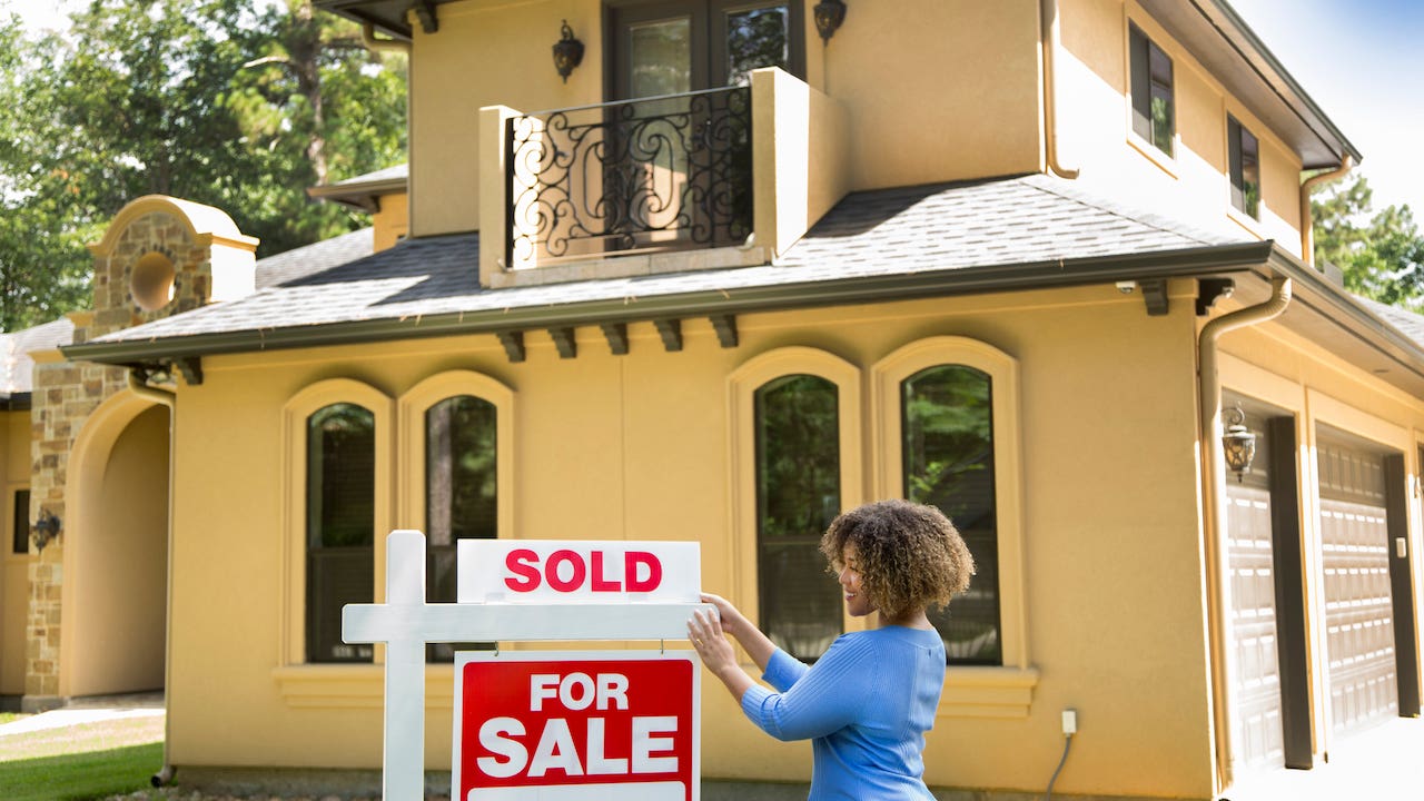 realtor adding "sold" sign to a home that's for sale