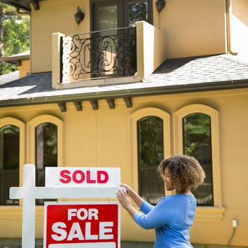 realtor adding "sold" sign to a home that's for sale