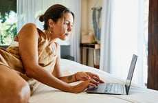 woman working on her laptop while relaxing on bed