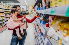 woman holding her young daughter while shopping at a grocery store