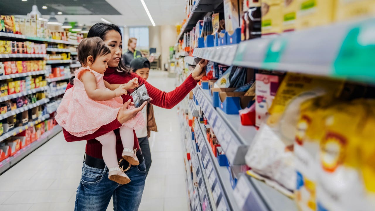 woman holding her young daughter while shopping at a grocery store