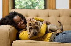 A woman lying on a couch at home with her pet dog